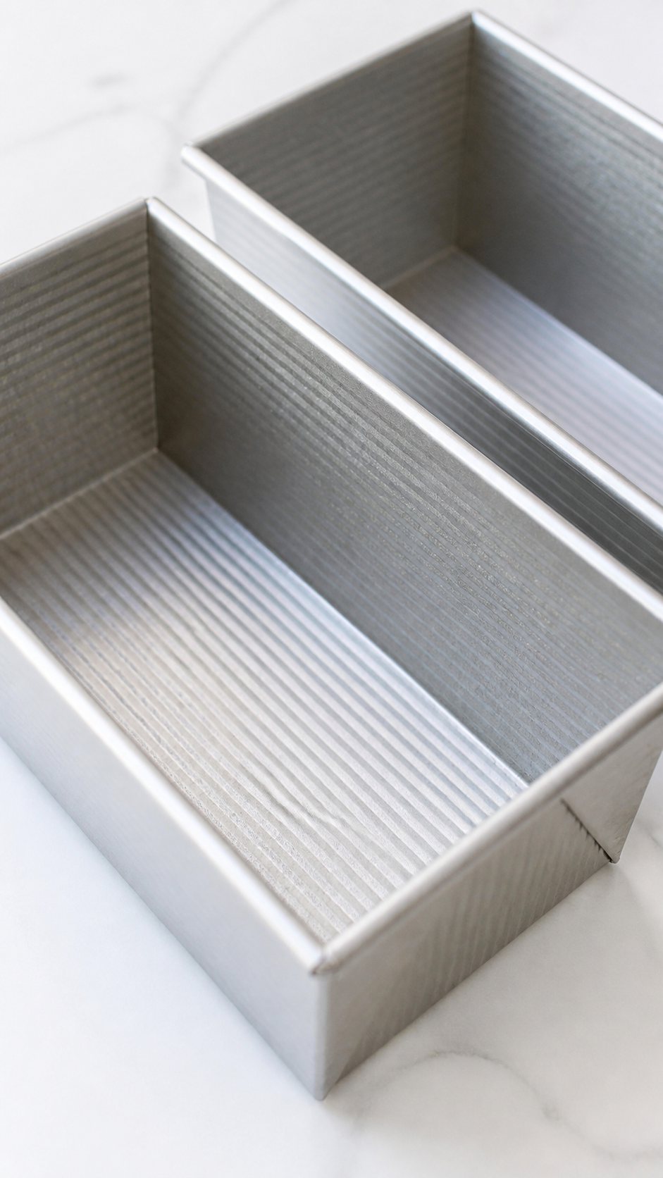Two greased 9x5-inch loaf pans prepared for pumpkin bread batter