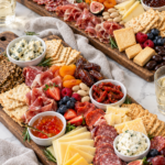 Two abundant charcuterie boards with cured meats, cheeses, fruit, spreads, and crackers.