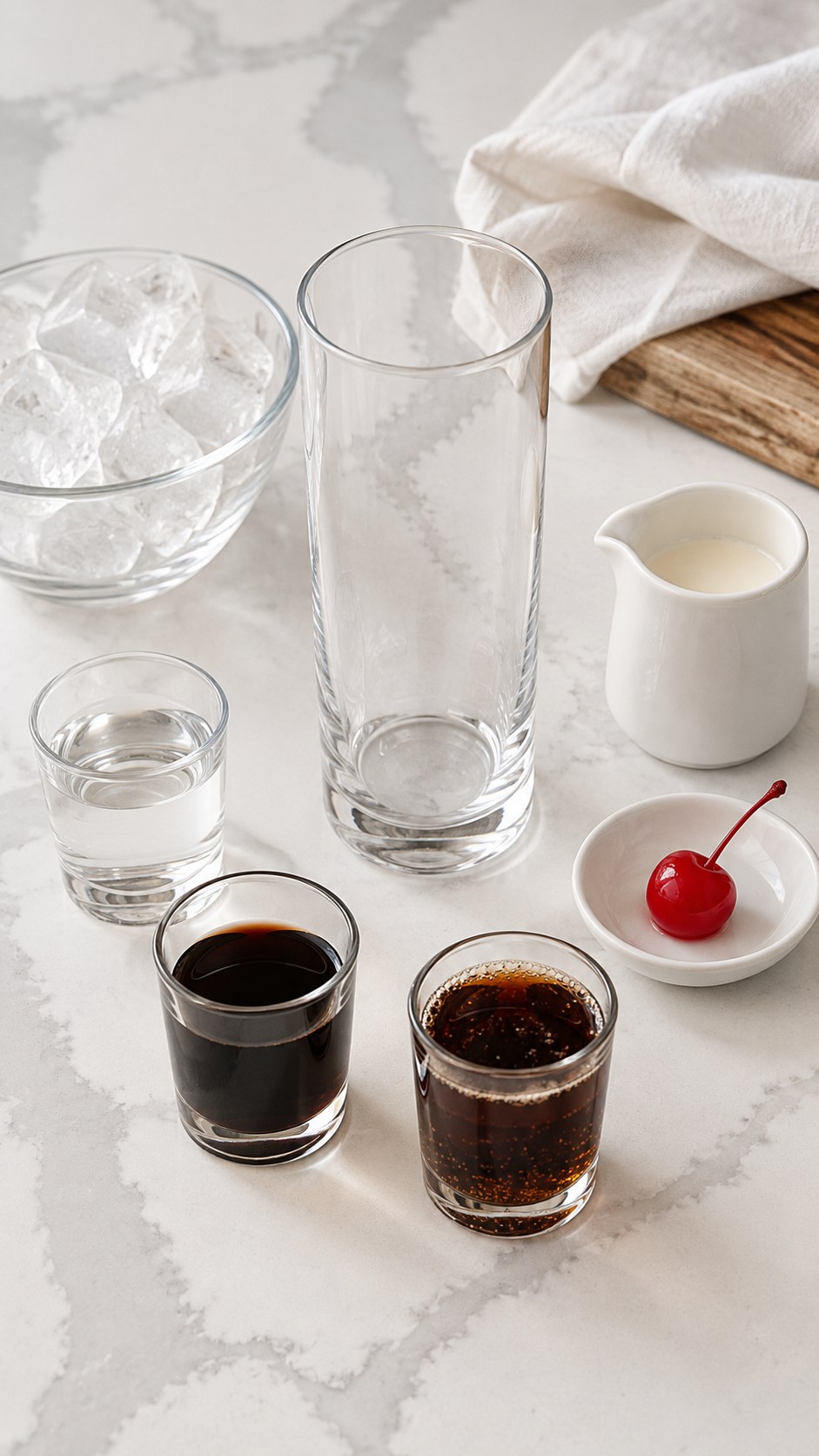 Vodka, Kahlua, Coca-Cola, light cream, one maraschino cherry, ice, and an empty highball glass.