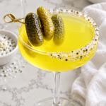 Finished dirty dill pickletini with a seasoned rim and three baby dill pickles.