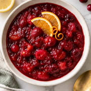 Overhead view of chunky cranberry sauce garnished with orange slices and zest curls