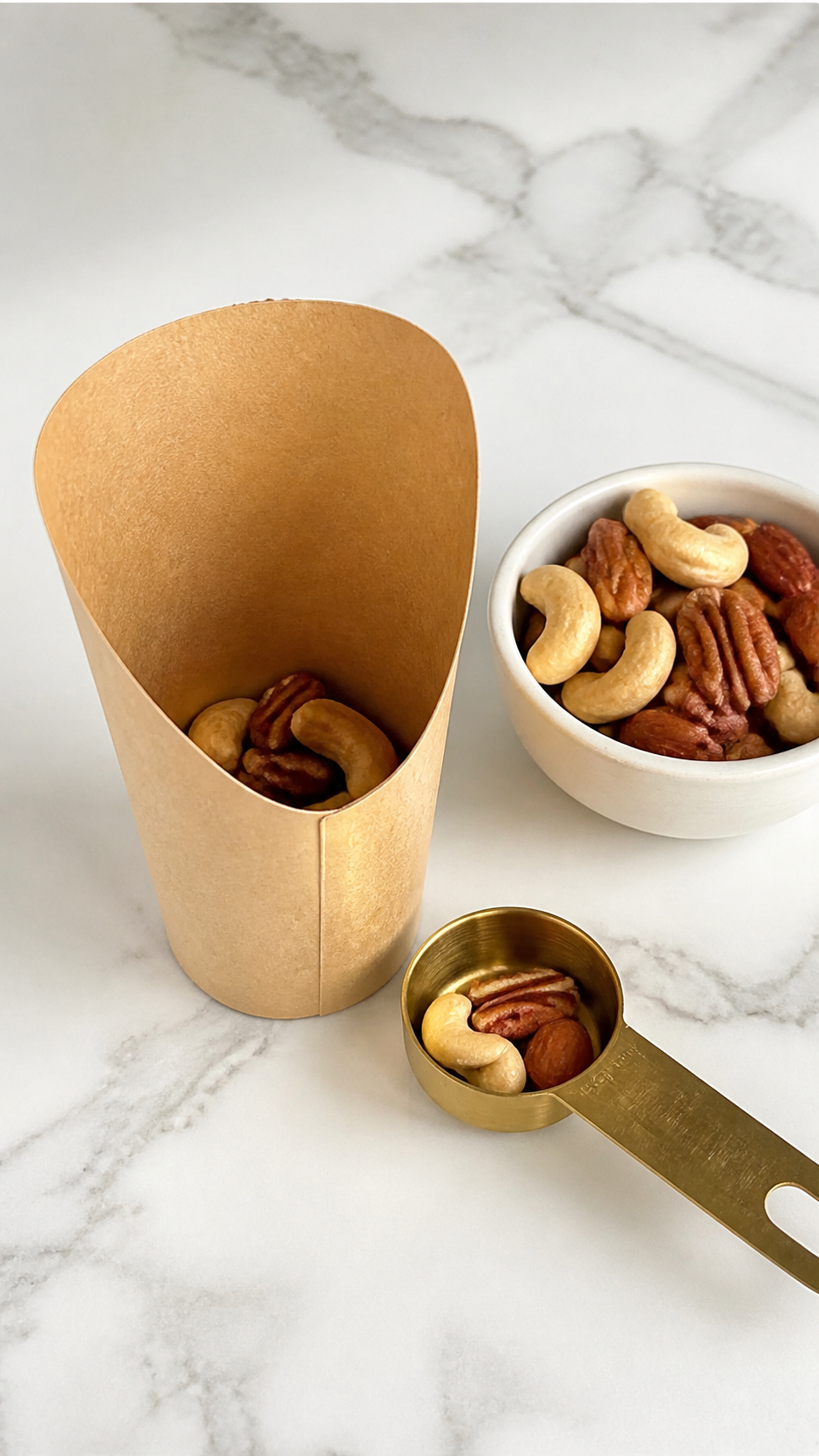Mixed nuts spooned into paper cups as the base for individual charcuterie cups.
