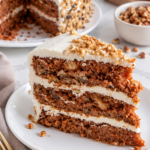 Close-up of carrot cake crumb and cream cheese frosting between three layers.