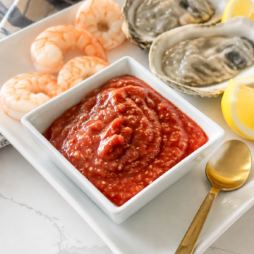 Homemade cocktail sauce served cold with boiled shrimp, oysters, and lemon wedges