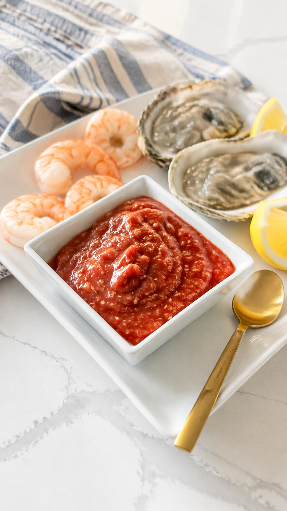 Homemade cocktail sauce served cold with boiled shrimp, oysters, and lemon wedges
