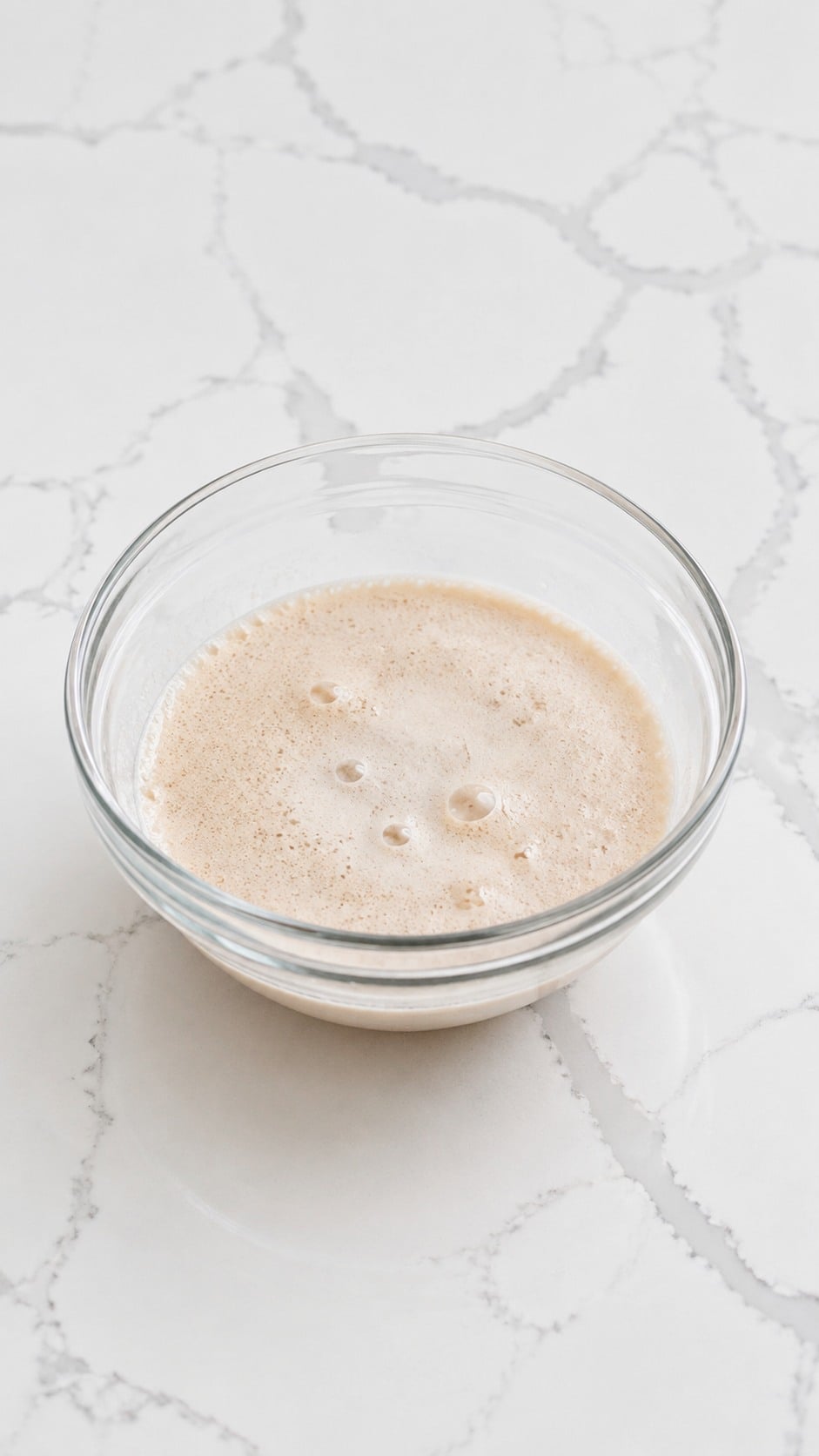 Foamy active dry yeast blooming with sugar in warm water.