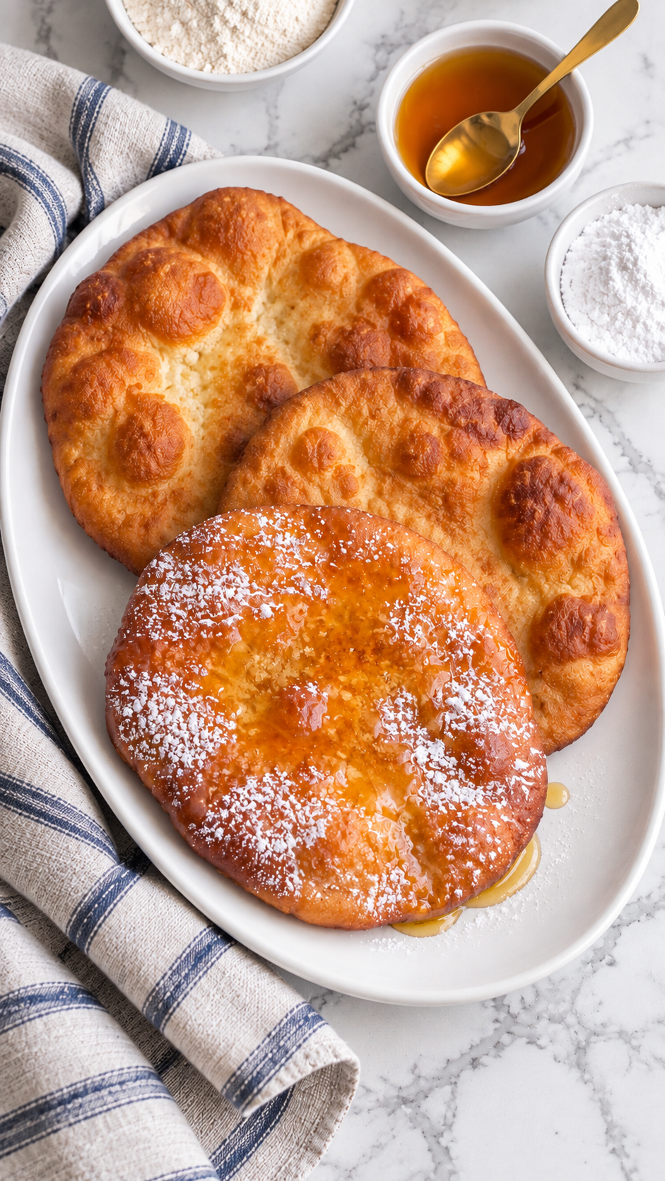 Overhead view of three golden fry bread rounds on a white platter.