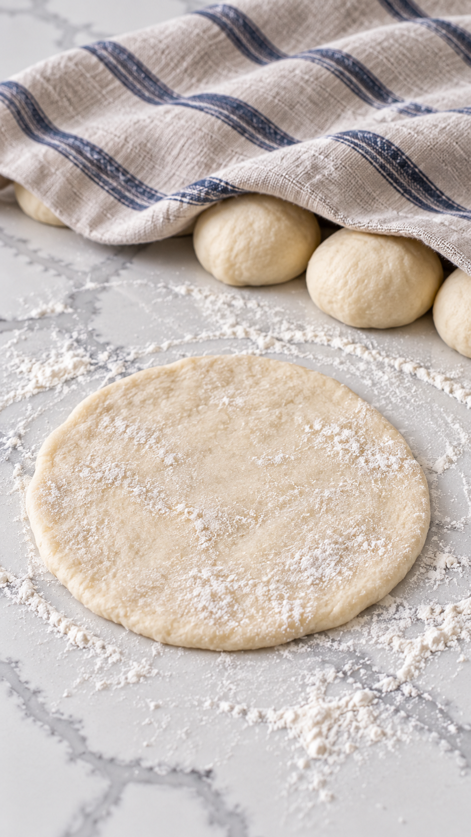A flattened raw fry bread round with covered dough portions behind it.