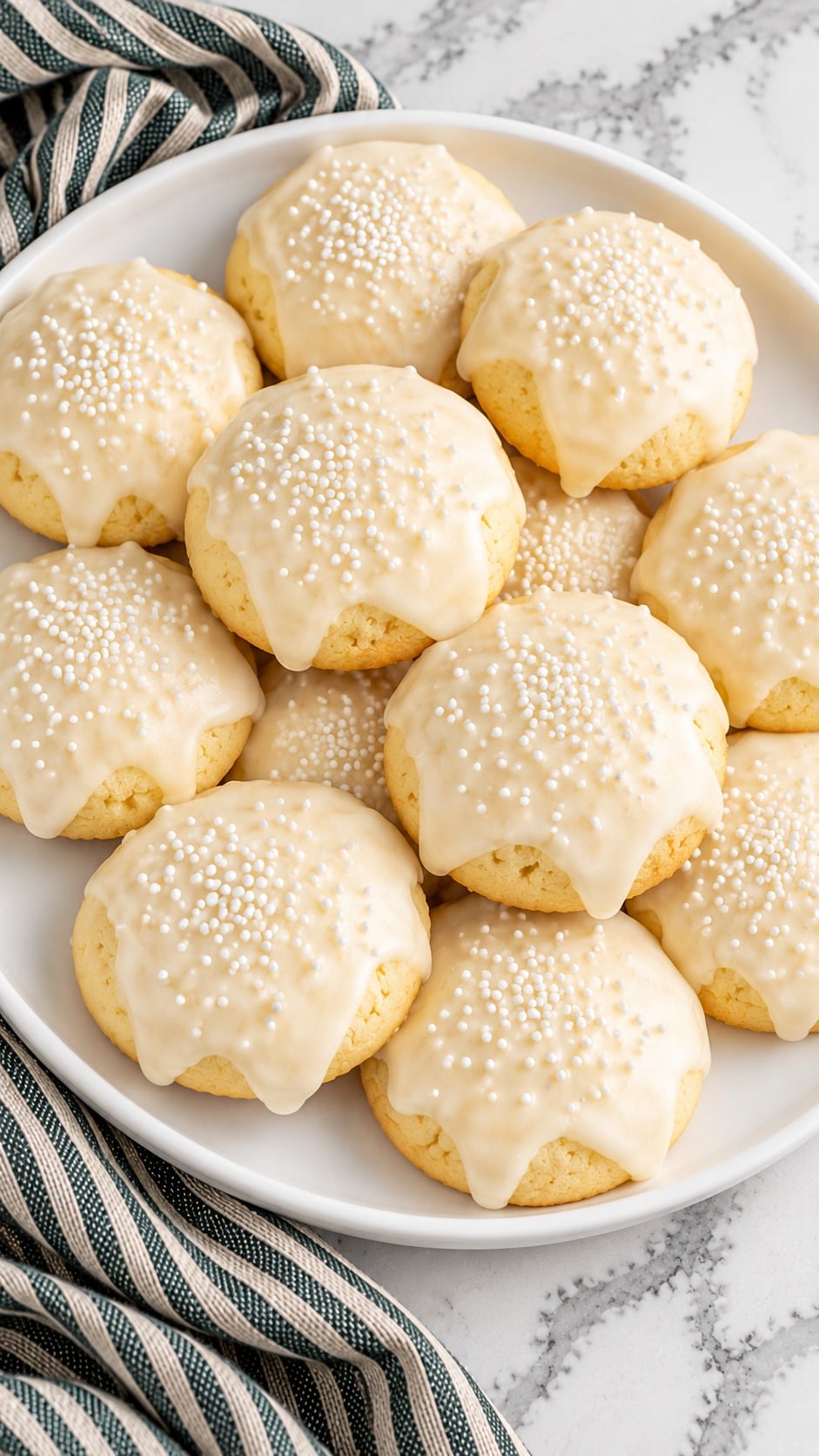 Close view of almond-iced Italian Christmas cookies with white sprinkles.