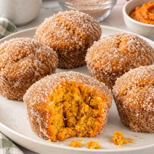 Pumpkin donut muffins with cinnamon sugar on an ivory platter, with orange crumb visible