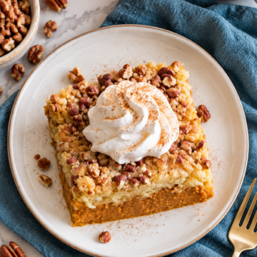 Overhead view of pumpkin dump cake with whipped cream on the same ivory dessert plate