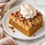 Pumpkin dump cake with a piped whipped cream swirl on a white ceramic plate