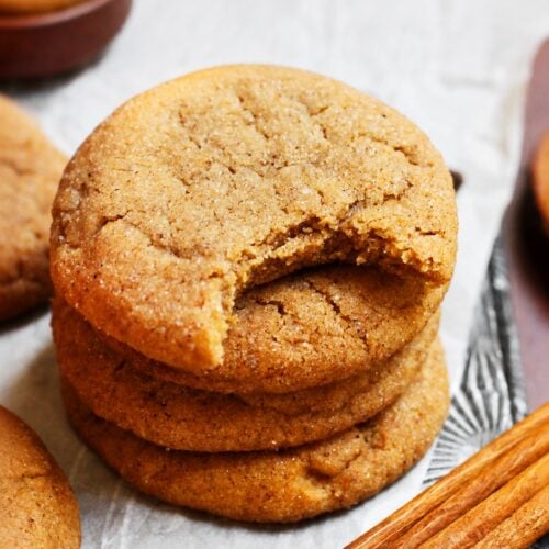 Stack of soft pumpkin spice cookies with a bitten cookie showing a dense chewy center.