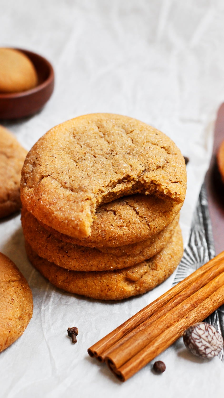 Stack of soft pumpkin spice cookies with a bitten cookie showing a dense chewy center.