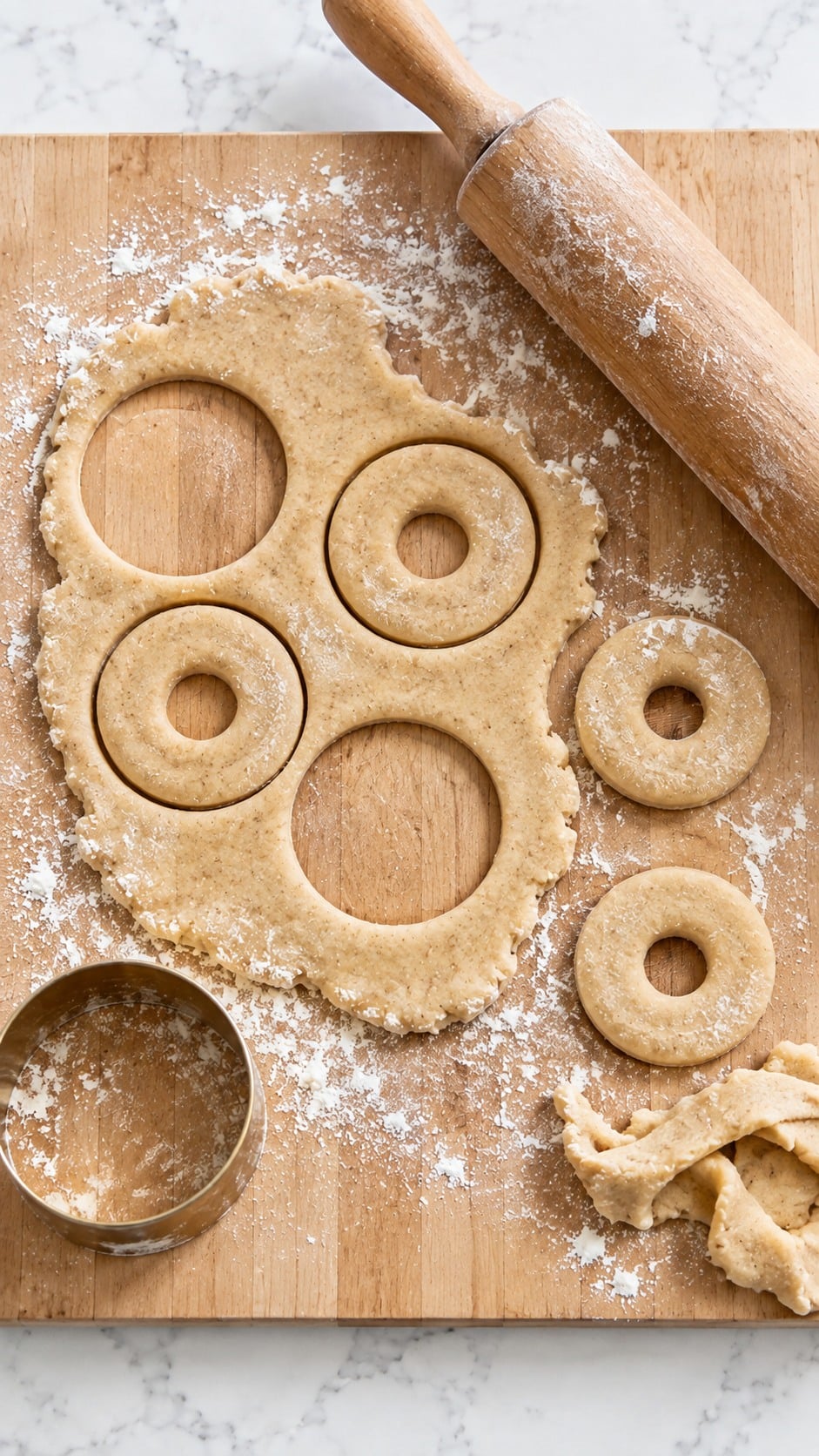 Chilled apple cider donut dough rolled and cut into rings on a floured board.