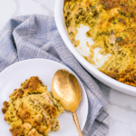 Cornbread dressing served on a white plate beside the baking dish