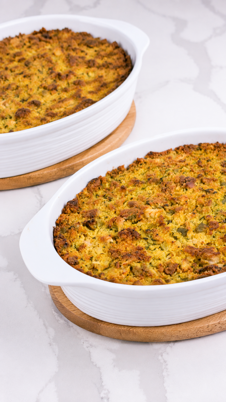 Two dishes of baked cornbread dressing with golden tops