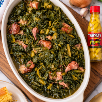 Alternate view of Southern collard greens in an ivory oval serving dish with Trappey’s pepper sauce