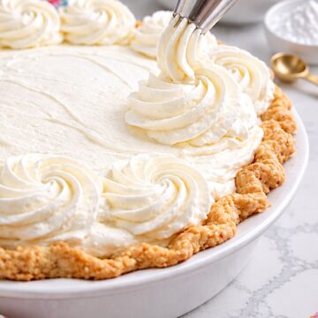 Piping stabilized whipped cream onto a pie with a star tip.