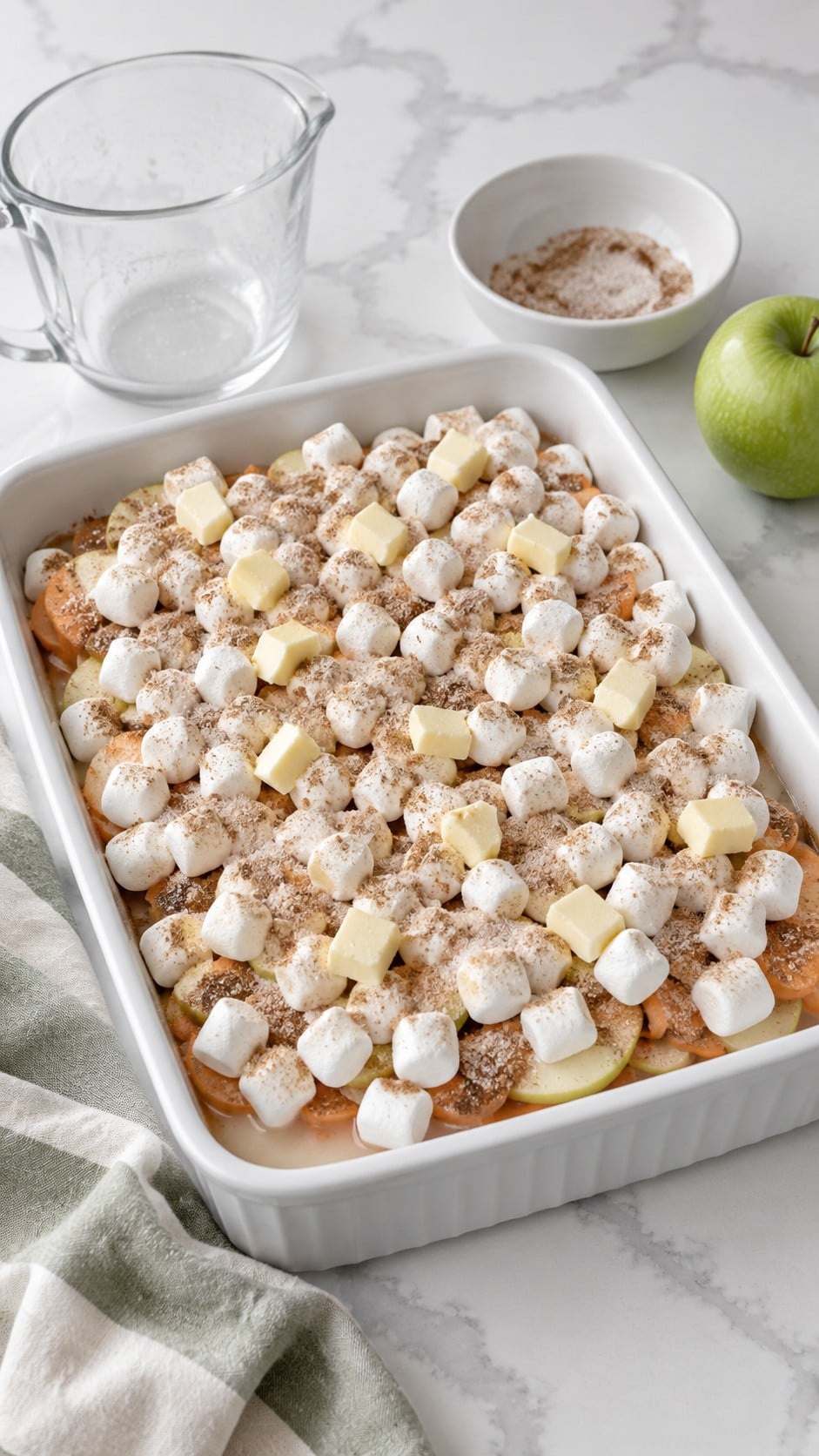 Layered casserole sprinkled with cinnamon sugar and dotted with butter before baking