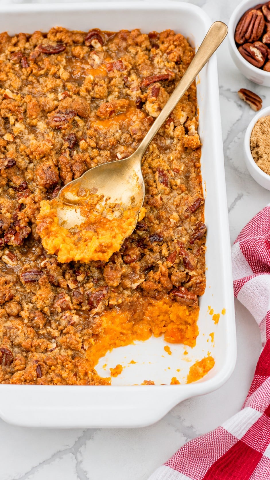 Sweet potato casserole with a serving removed from the white dish