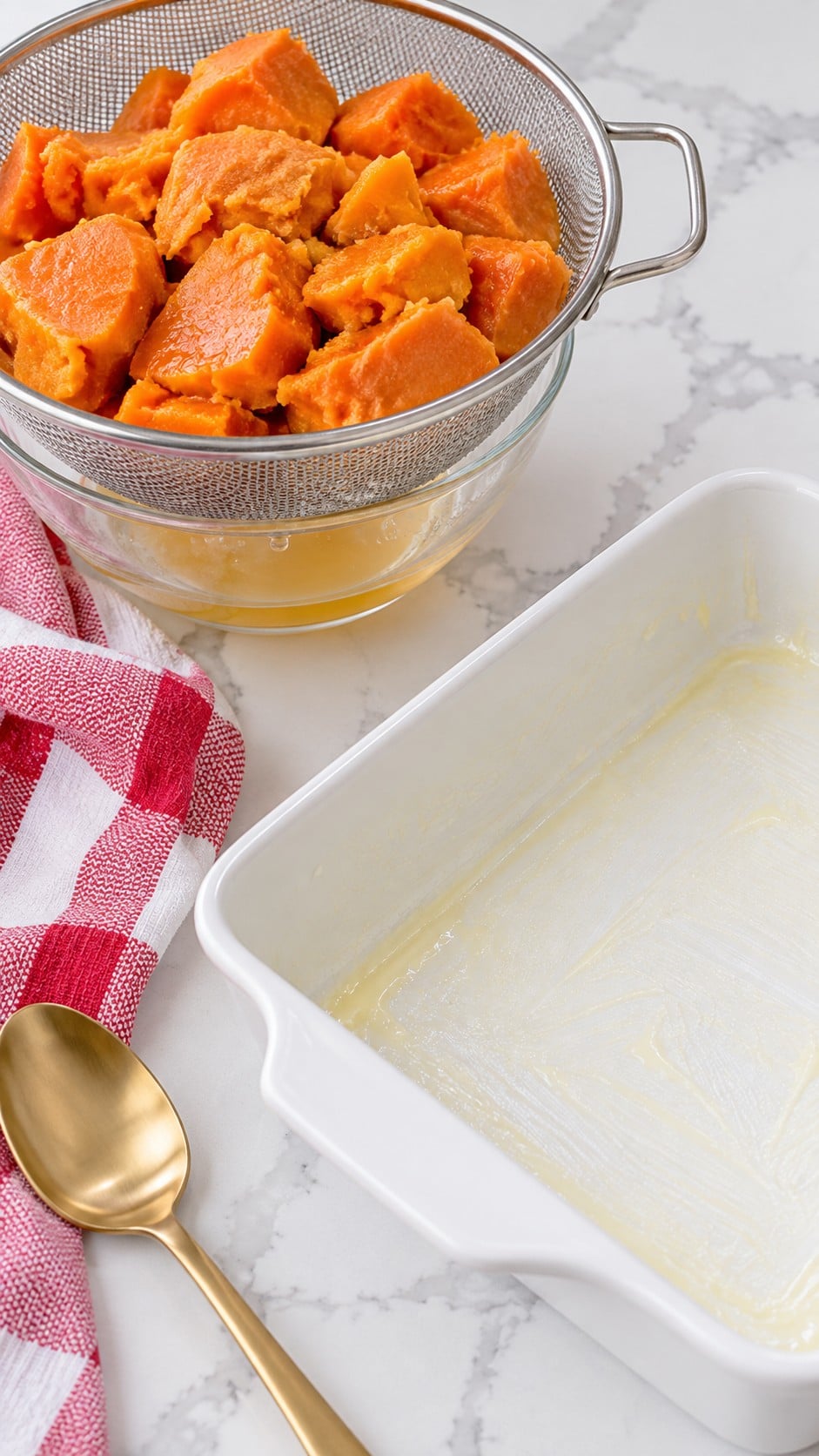 Drained sweet potatoes beside a greased baking dish