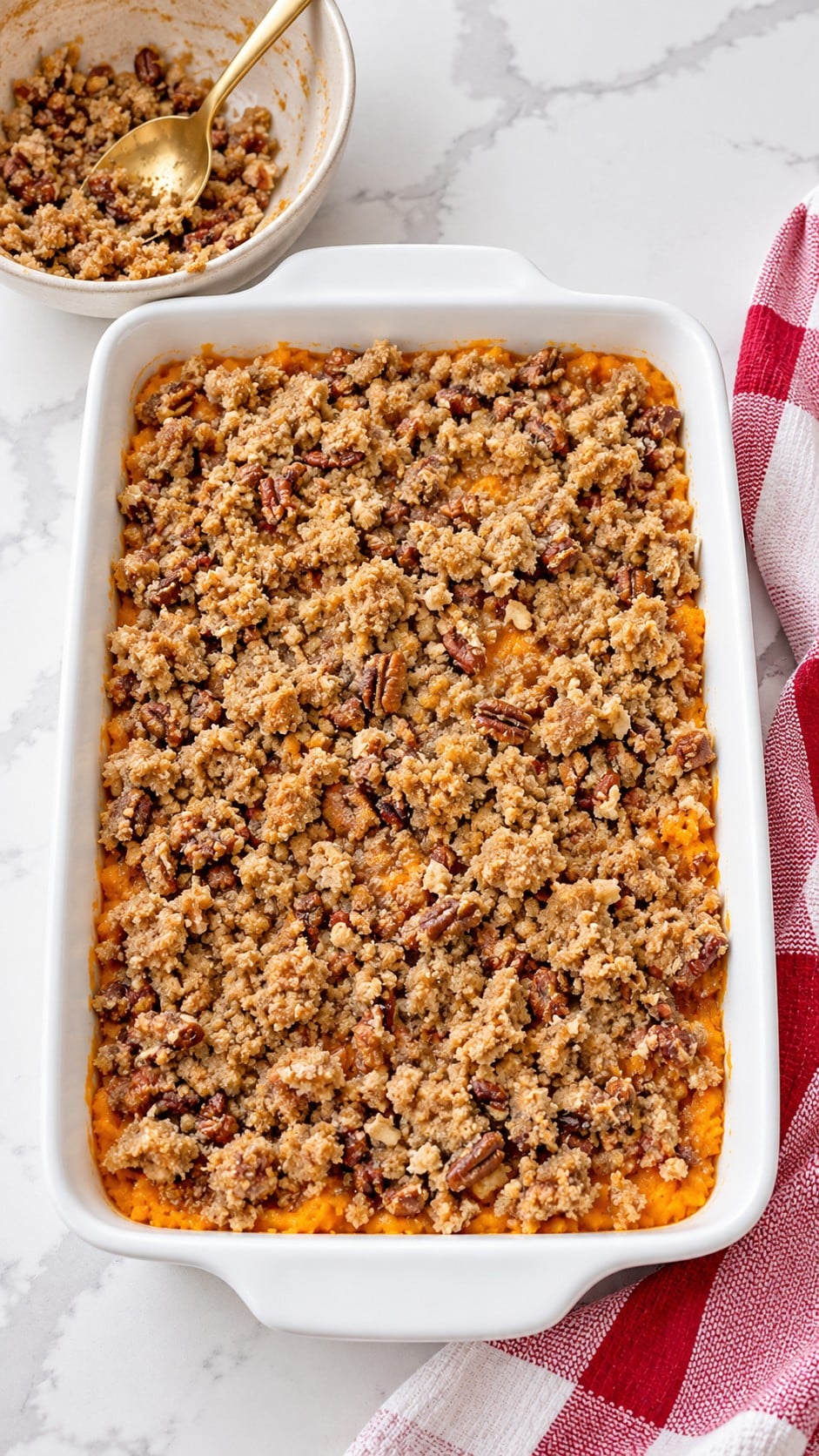 Unbaked pecan streusel scattered over sweet potato filling