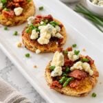 Close view of toasted cranberry-pistachio bread with fig jam, crisp bacon, and softened blue cheese.