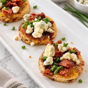 Close view of toasted cranberry-pistachio bread with fig jam, crisp bacon, and softened blue cheese.