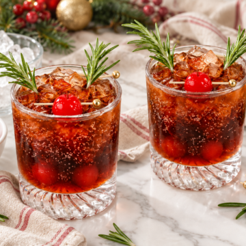 Two Dirty Rudolph cocktails with two rosemary antlers and a centered cherry nose on each glass