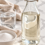 Clear double rich simple syrup in a swing-top bottle beside sugar and water