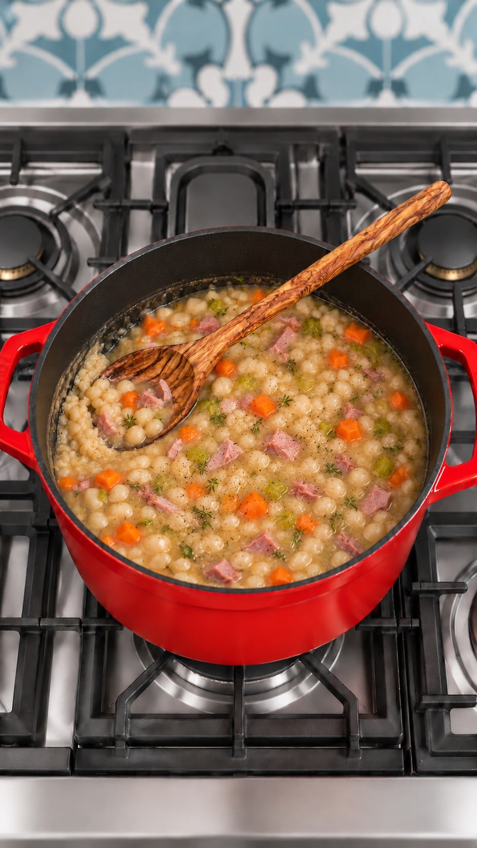 A wooden spoon mashing some navy beans to thicken the soup after adding ham.