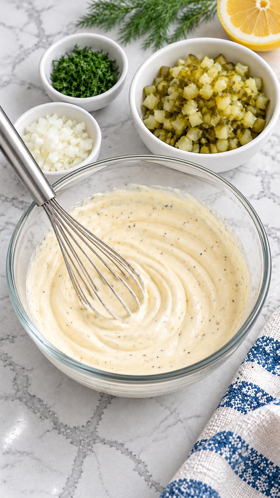 Mayonnaise and seasonings whisked smooth in a glass bowl before adding pickles, onion, and dill.