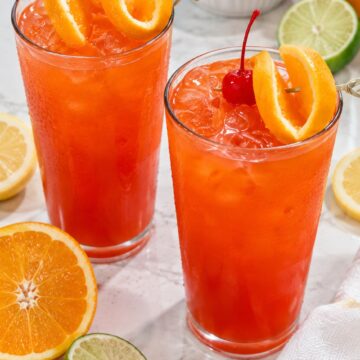 Two glasses of Jamaican rum punch with orange and cherry garnishes