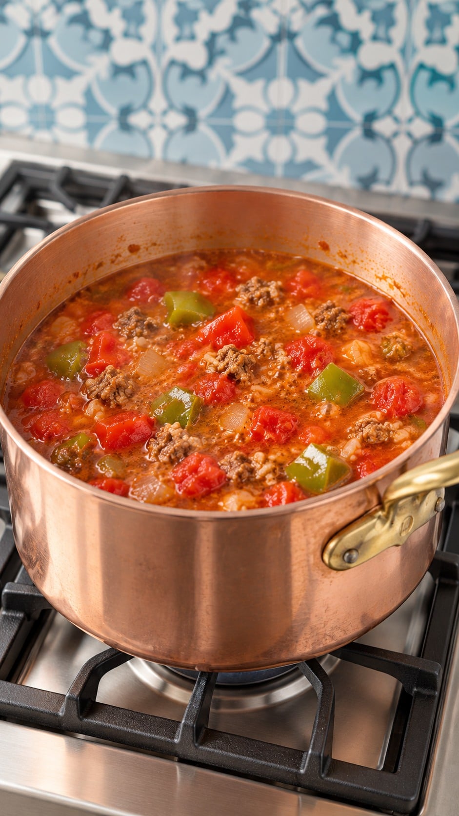 Tomato broth with beef, sausage, and bell peppers simmering before the rice is added.