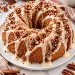 Spiral sweet potato pecan pound cake with thick creamy buttermilk glaze and chopped pecans on a white platter.