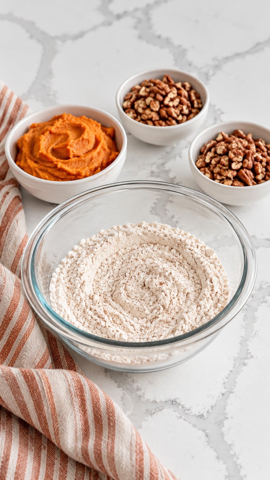 Flour and spice mixture beside smooth sweet potato puree and two portions of chopped pecans.